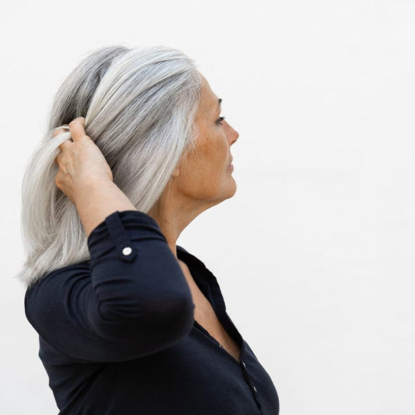 Woman with grey hair in side profile, representing menopause and life stages of the vaginal microbiome