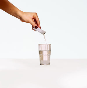 Hand pouring an Ultimate UT probiotic sachet into a glass of water